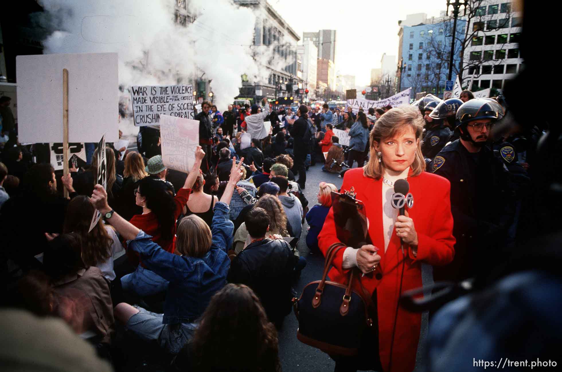 Television reporter in the middle of sit-down protest on Market Street at Gulf War protest.