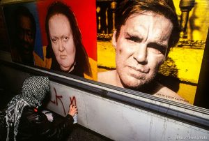 Gulf War protester spray-painting on bus with funny people sign.