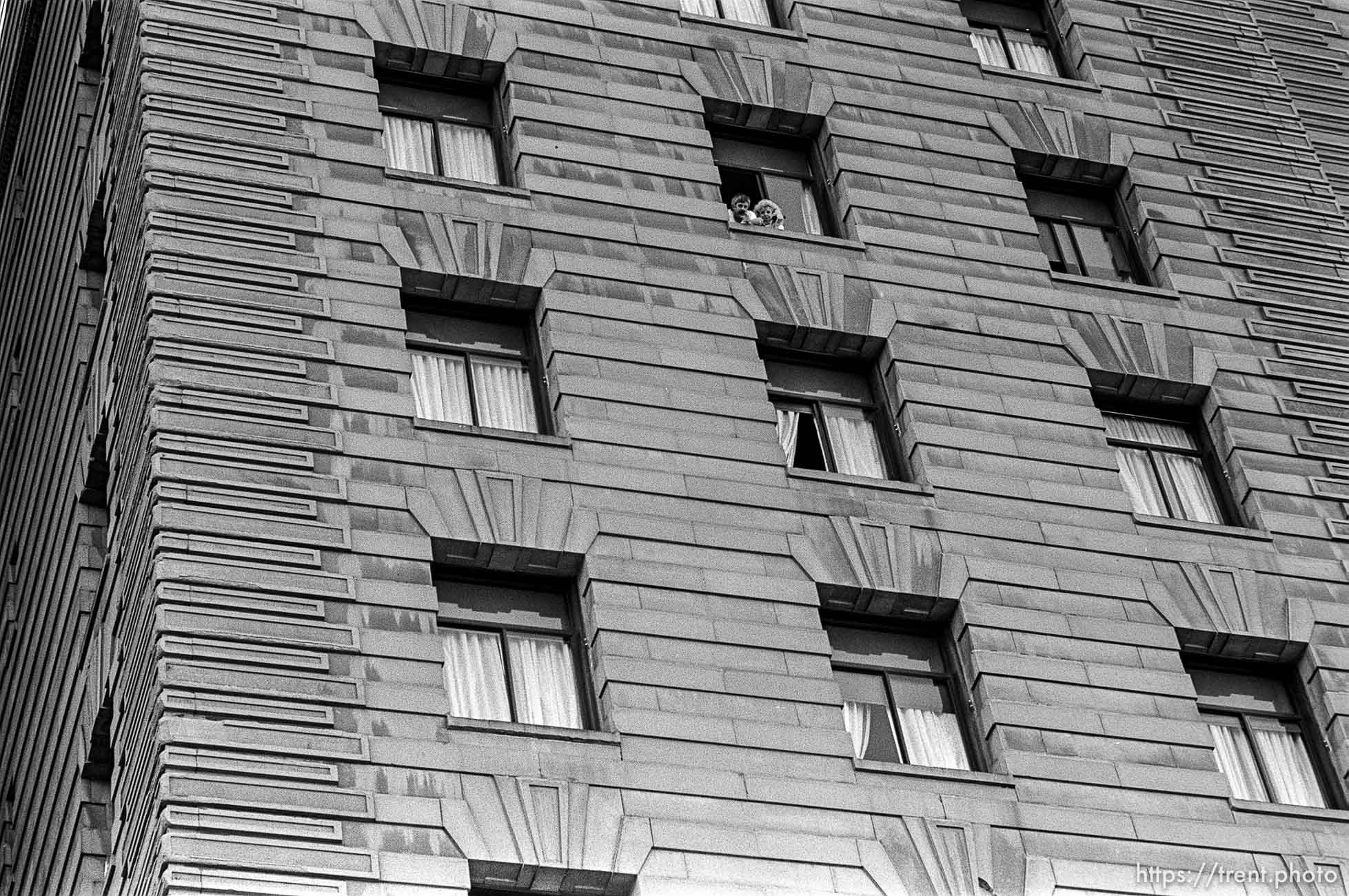 People looking out of hotel window at Act-Up protest during visit of President Bush