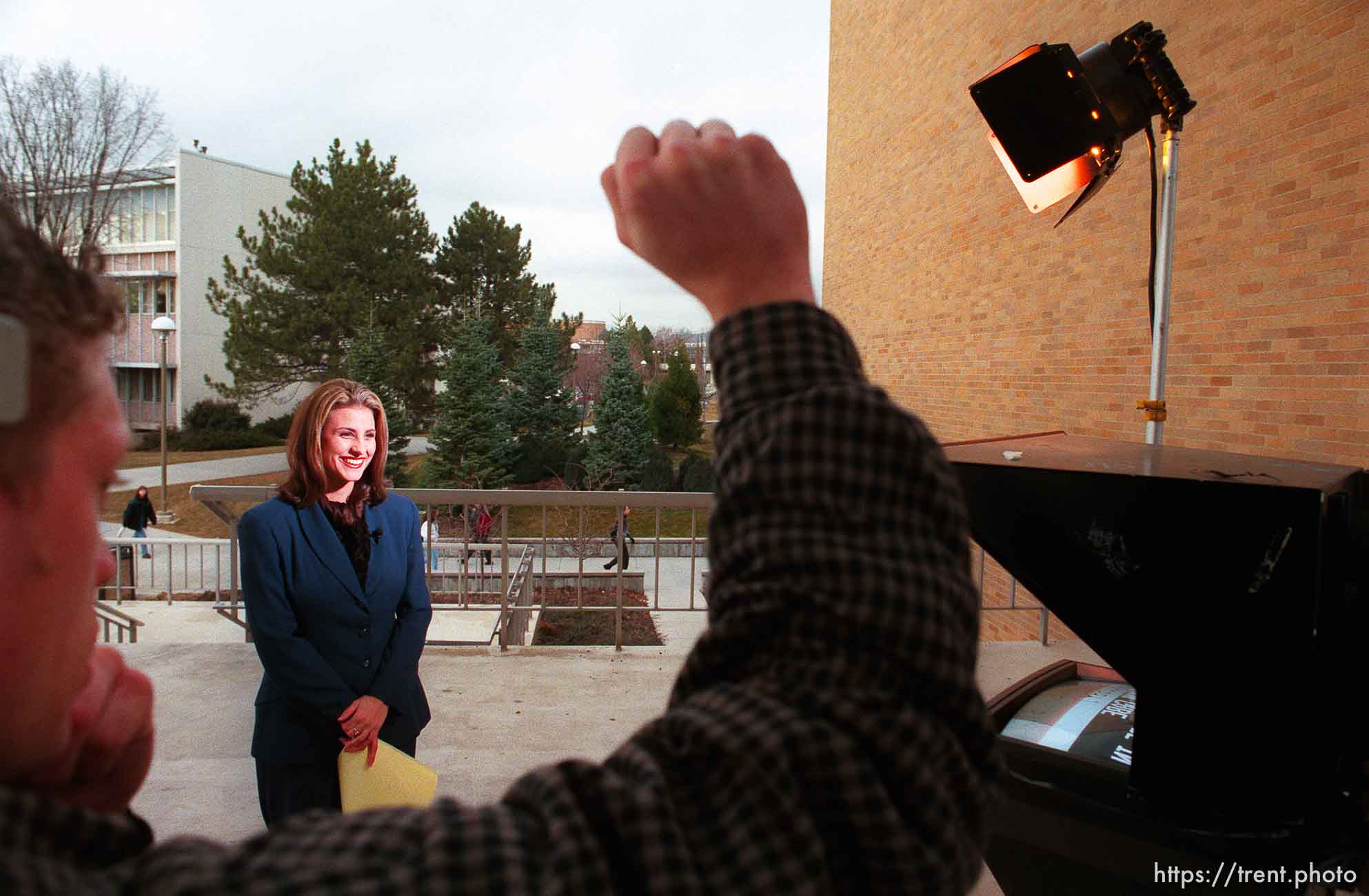 Floor director Christopher Hatch signals to Libby Wood during the taping of a remote news broadcast at KBYU TV.