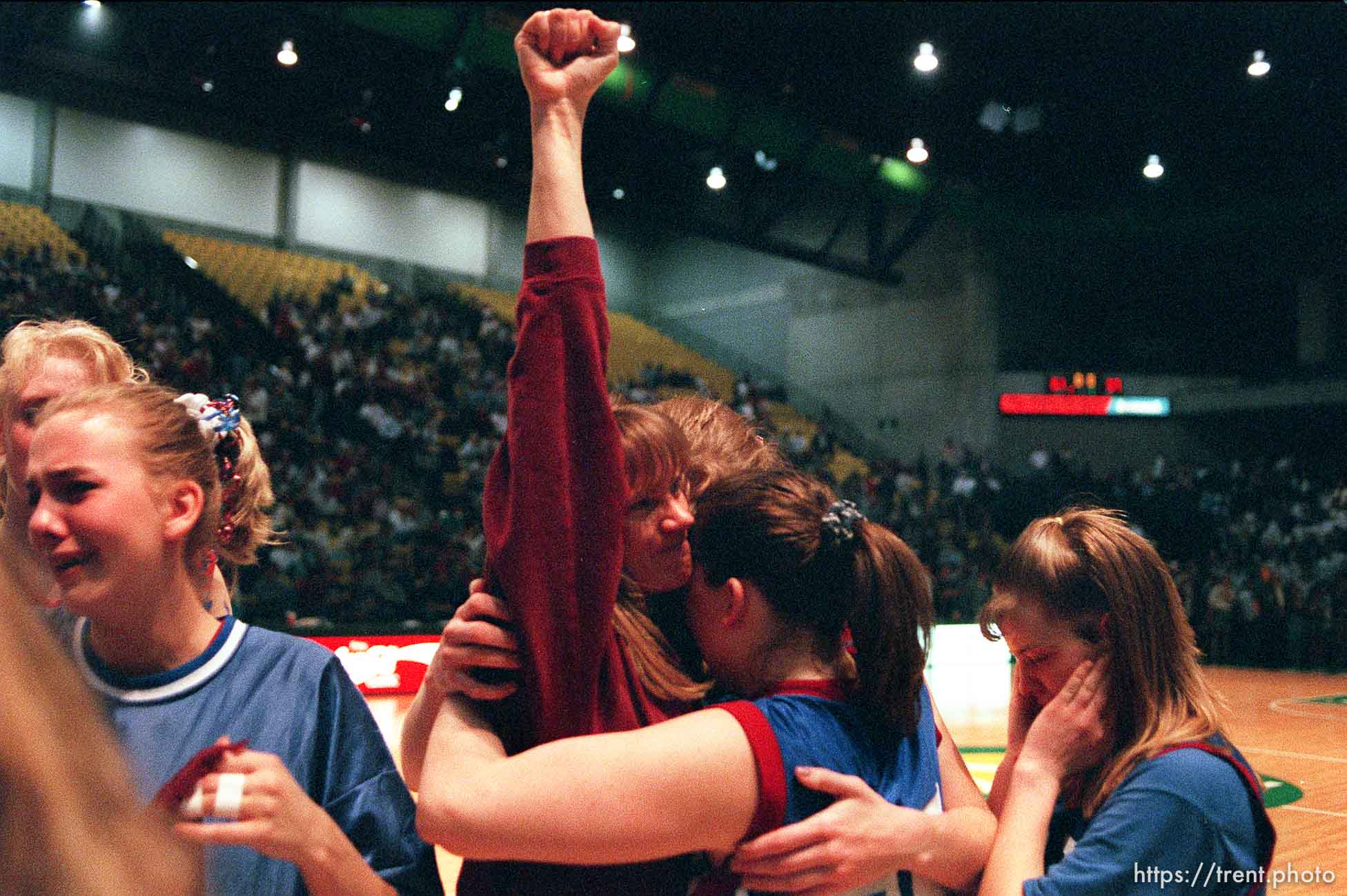 North Sevier girls' basketball coach Lexa Larsen raises her first to the Wolves' fans after losing in the state championship game to Beaver. Embracing the coach are Shadoe Shaheen (25) and Ann Braithwaite. At right is Chasity Peterson.