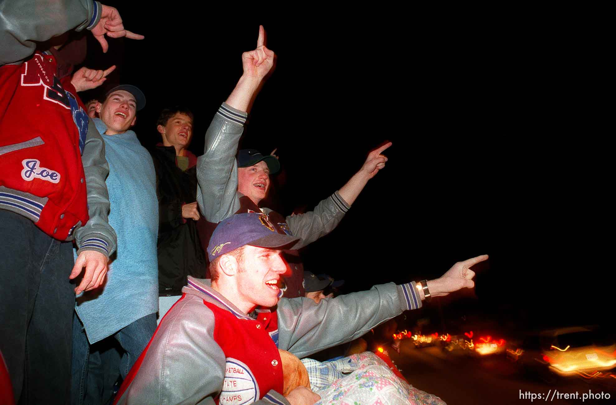 Sirens and horns wake up sleepy Salina at midnight as members of the two-time state champion North Sevier boys basketball team ride a fire truck through town, followed by approximately 100 cars. In this photo, the fire truck has doubled back on the route. The cars at lower right are part of the parade.