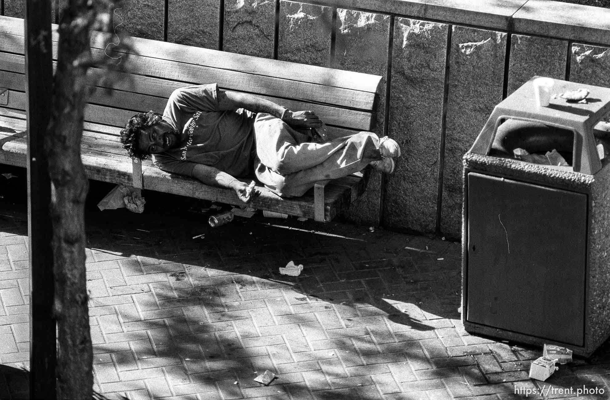 Hysterical man eating pizza on a bench.