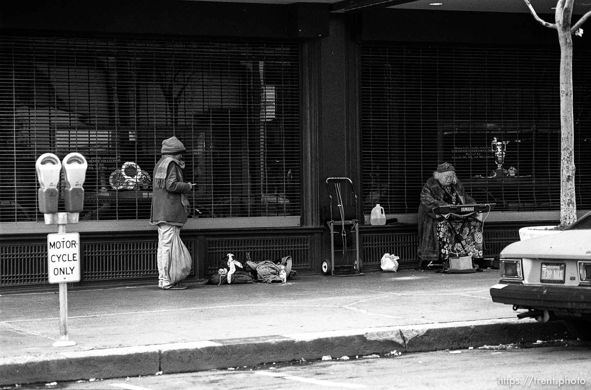 Homeless person and old lady playing a keyboard on the street.