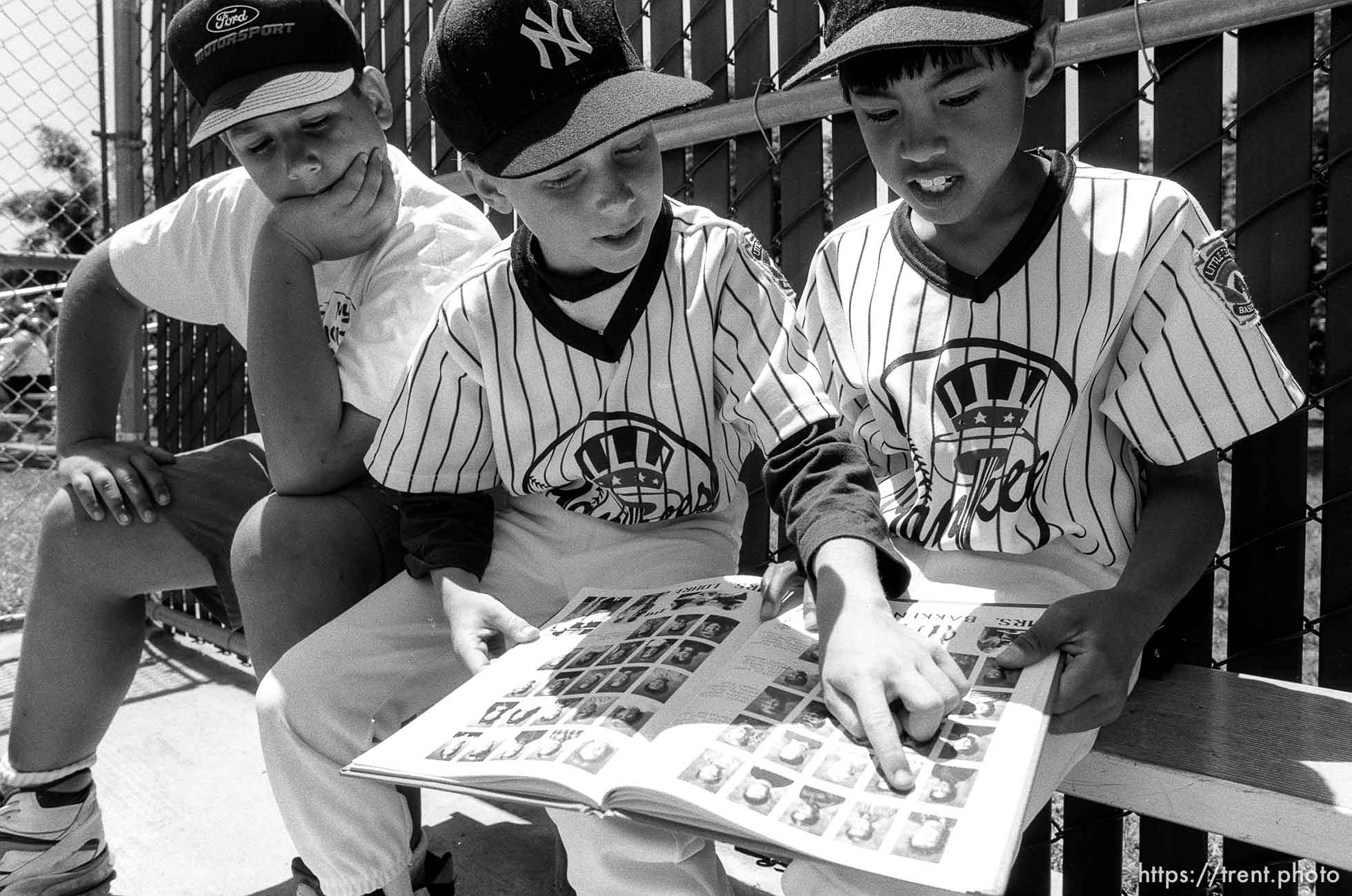 Kids reading yearbook in dugout at Yankees baseball game.