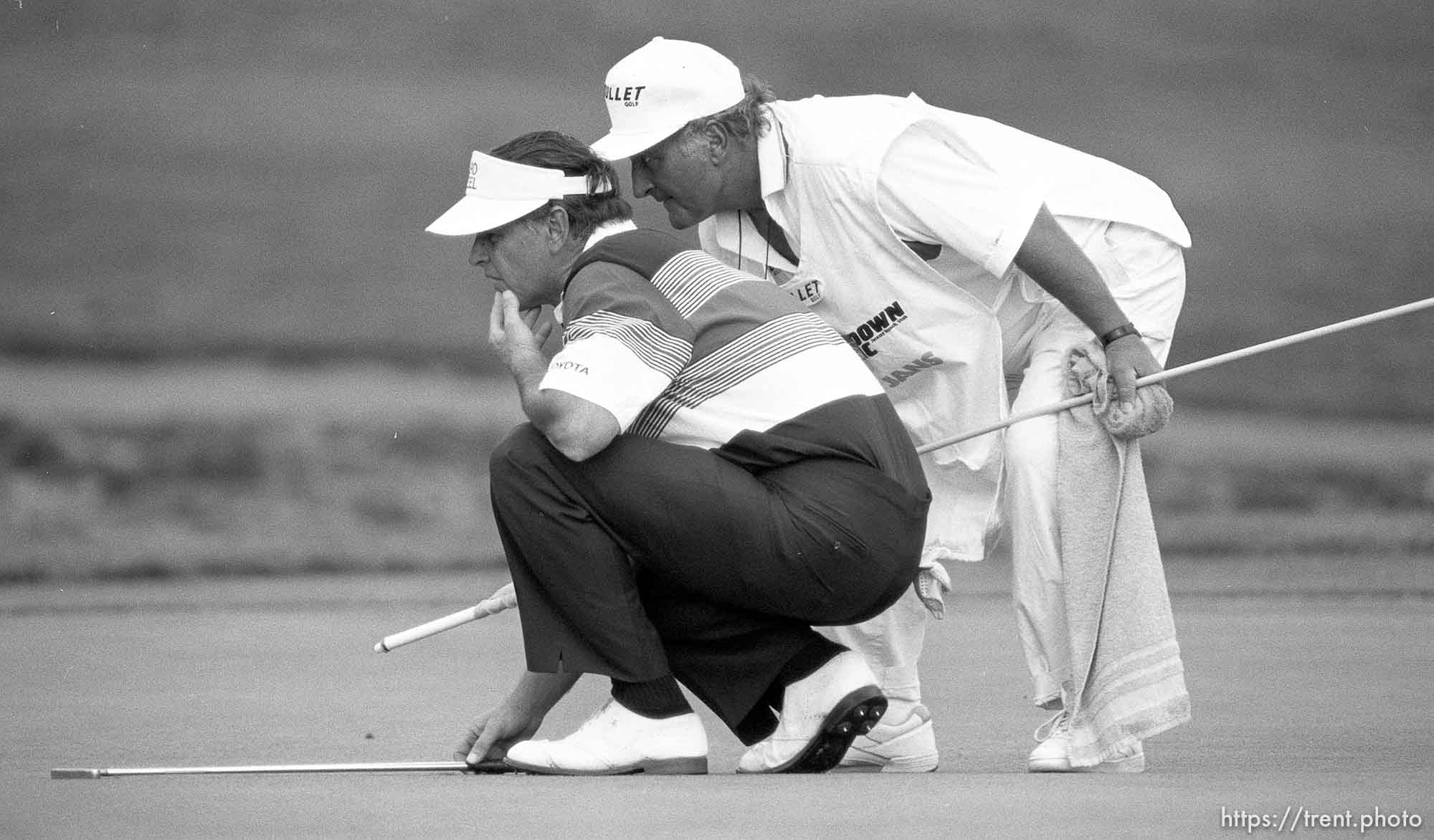 Golfer and caddy line up a putt at PGA golf tournament.