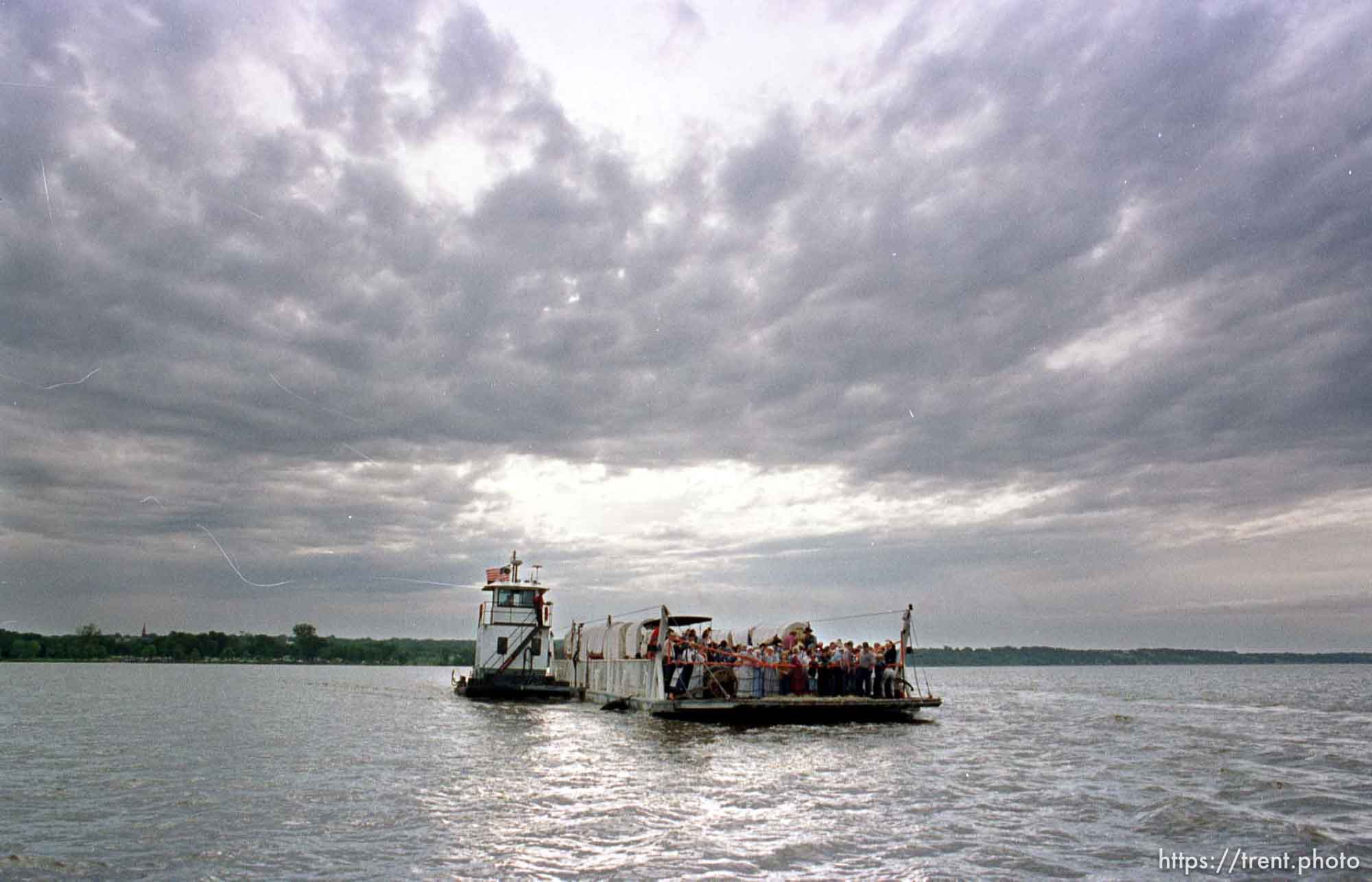 A ferry carrying the members, horses, and wagons of the JL2 Authentic Wagon Train crosses the Mississippi River en route to beginning their trek across Iowa. photo by trent nelson