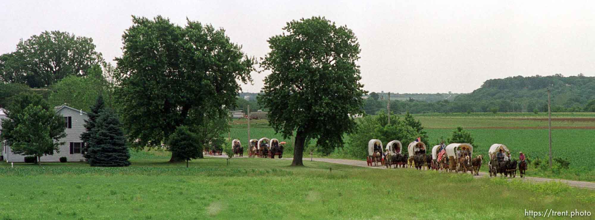 The JL2 Authentic Wagon Train passes a small farmhouse as it makes its way down Peach Orchard Road in rural Iowa after crossing the Mississippi by ferry. photo by trent nelson