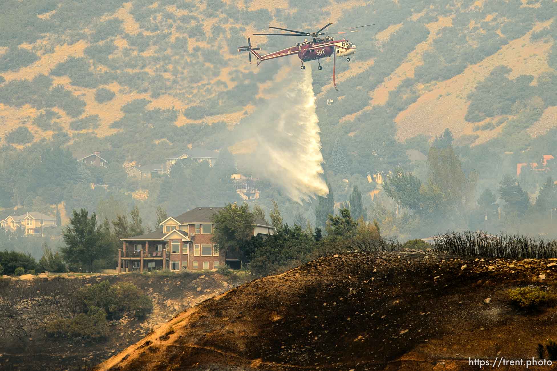 (Trent Nelson | The Salt Lake Tribune)  A helicopter dumps water on homes at the mouth of Weber Canyon, Tuesday September 5, 2017.