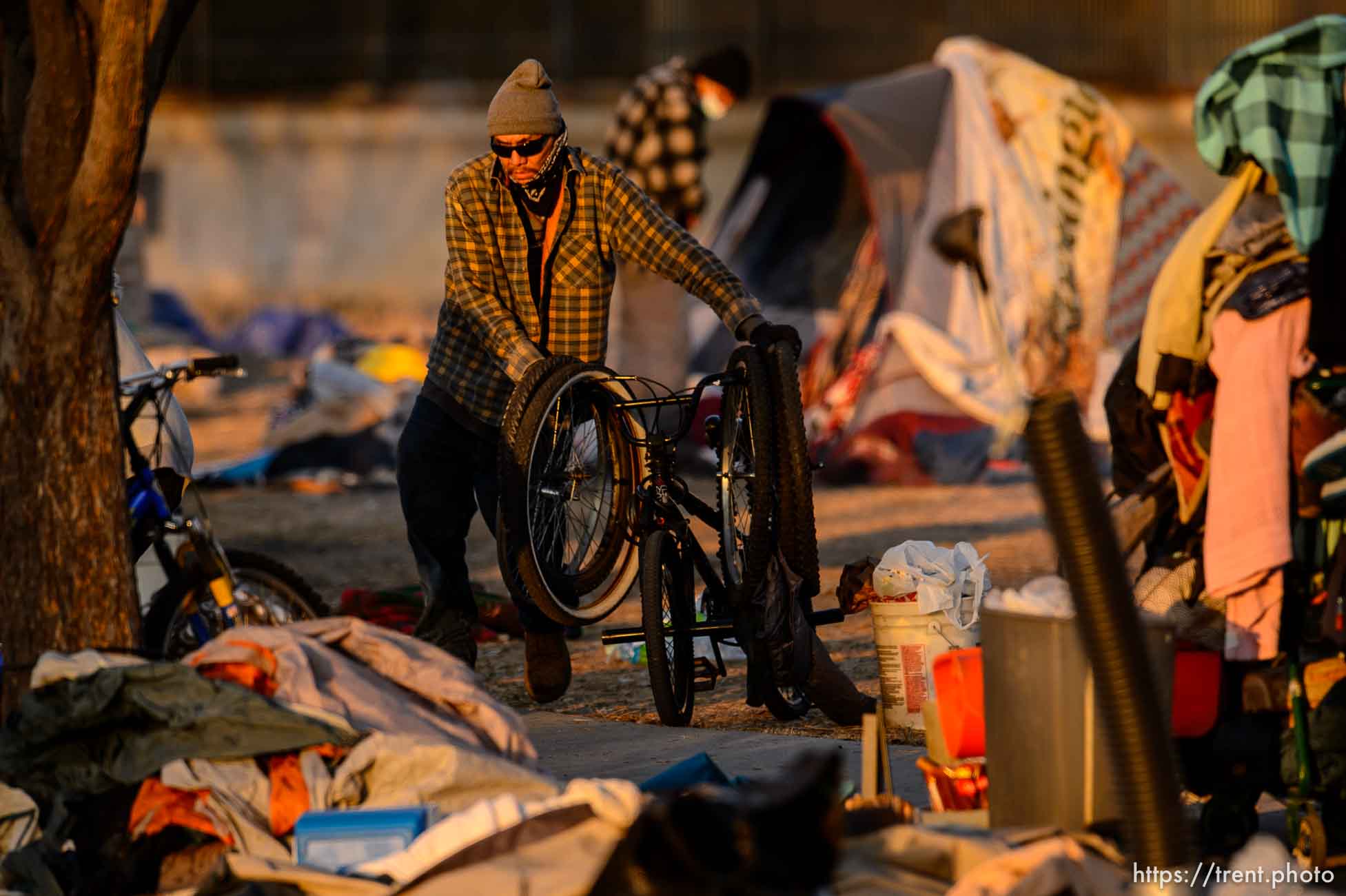 (Trent Nelson  |  The Salt Lake Tribune) A man  moves a bike and several tires as a cleanup crew from the health department approaches, in Salt Lake City on Wednesday, Dec. 9, 2020.