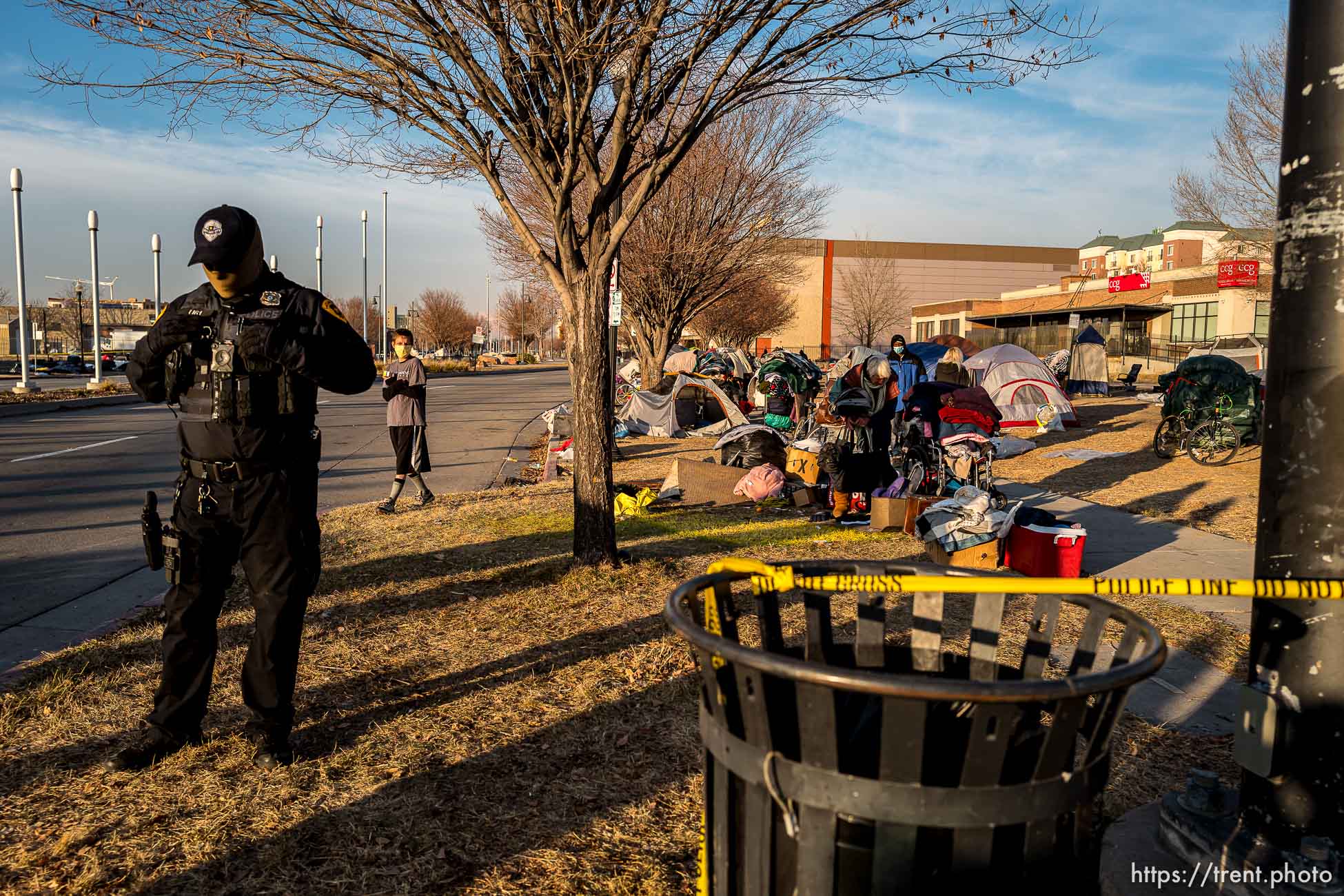 (Trent Nelson  |  The Salt Lake Tribune) A Salt Lake City police officer stands near campsites in the Rio Grande area of Salt Lake City before health workers swept through in a clean up operation on Wednesday, Dec. 9, 2020.