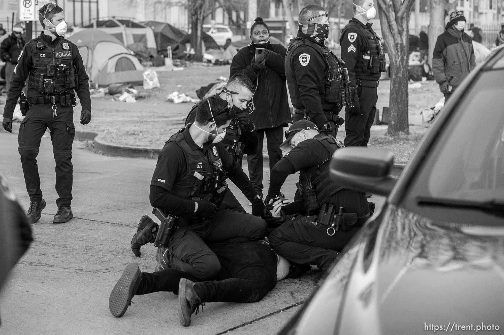 (Trent Nelson  |  The Salt Lake Tribune) Salt Lake City police officers working the cleanup of a series of campsites in Salt Lake City on Wednesday, Dec. 9, 2020. An activist is arrested after a group stood in front of a police car, not allowing it to pass.