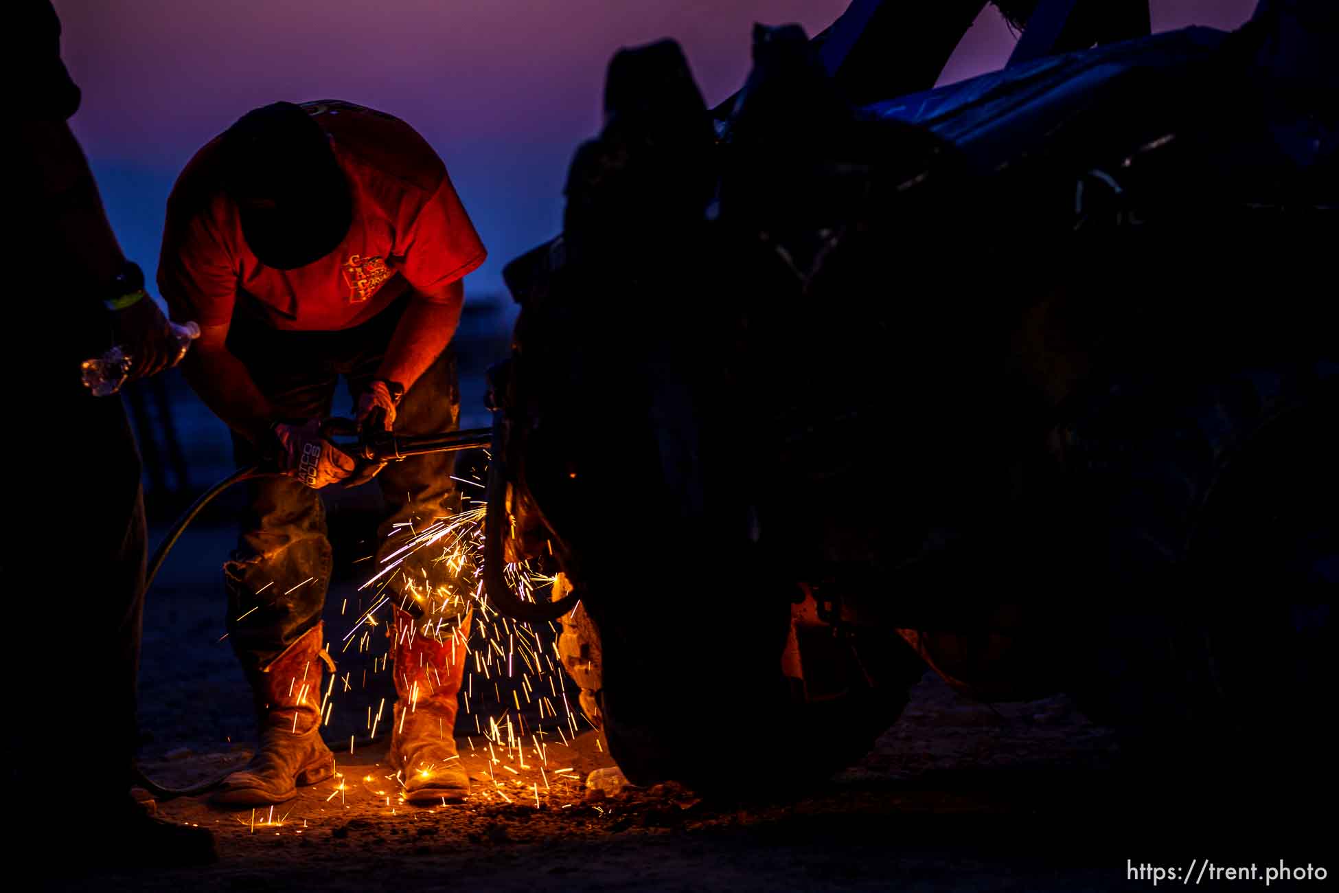 (Trent Nelson  |  The Salt Lake Tribune) John Gullo works to get his son's car back into working condition during Punishment at the Peak, a demolition derby in Grantsville on Saturday, Aug. 7, 2021.