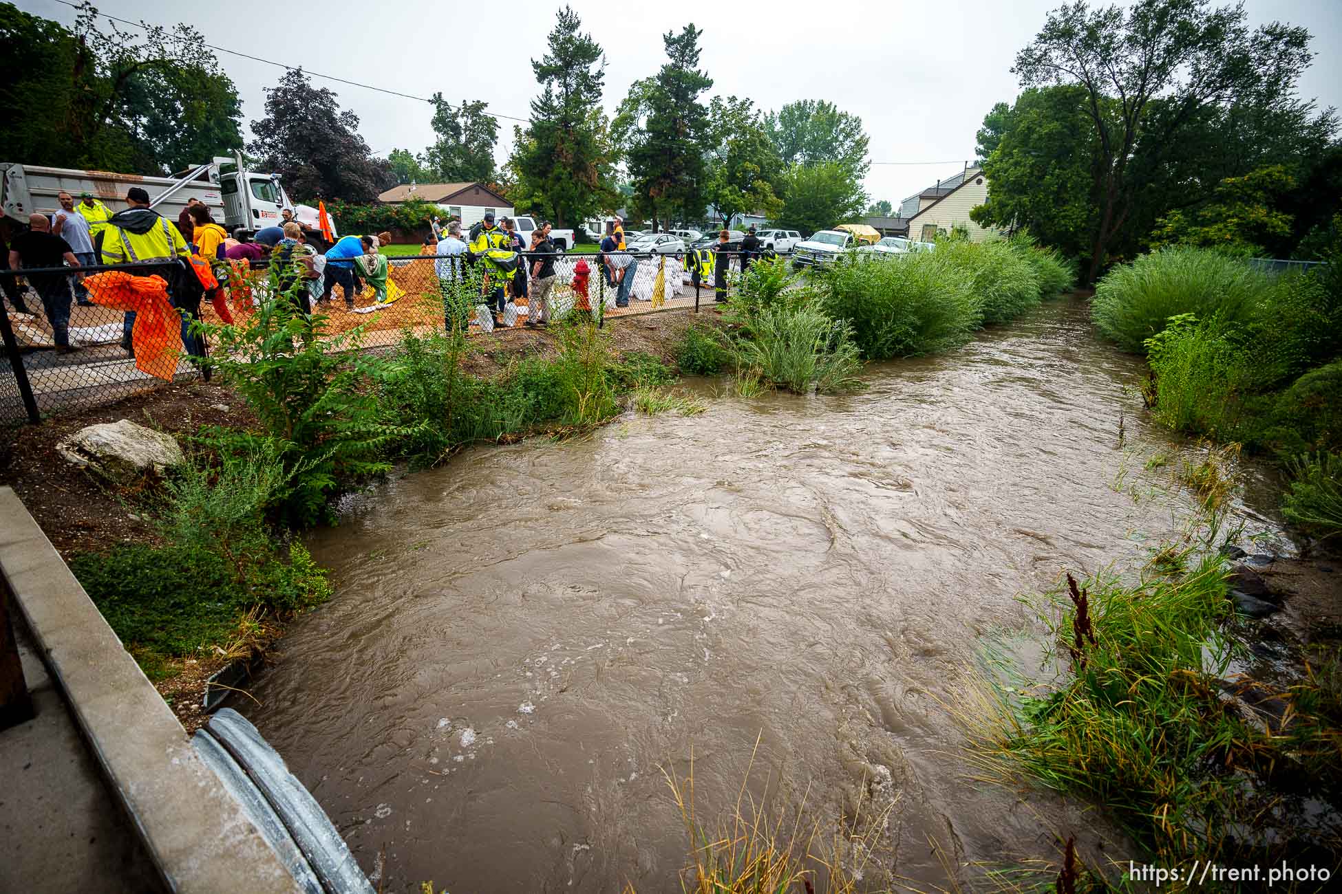 (Trent Nelson  |  The Salt Lake Tribune) Firefighters, public works employees, and volunteers fill sandbags next to a swollen Mill Creek in South Salt Lake after heavy rains on Wednesday, Aug. 18, 2021.