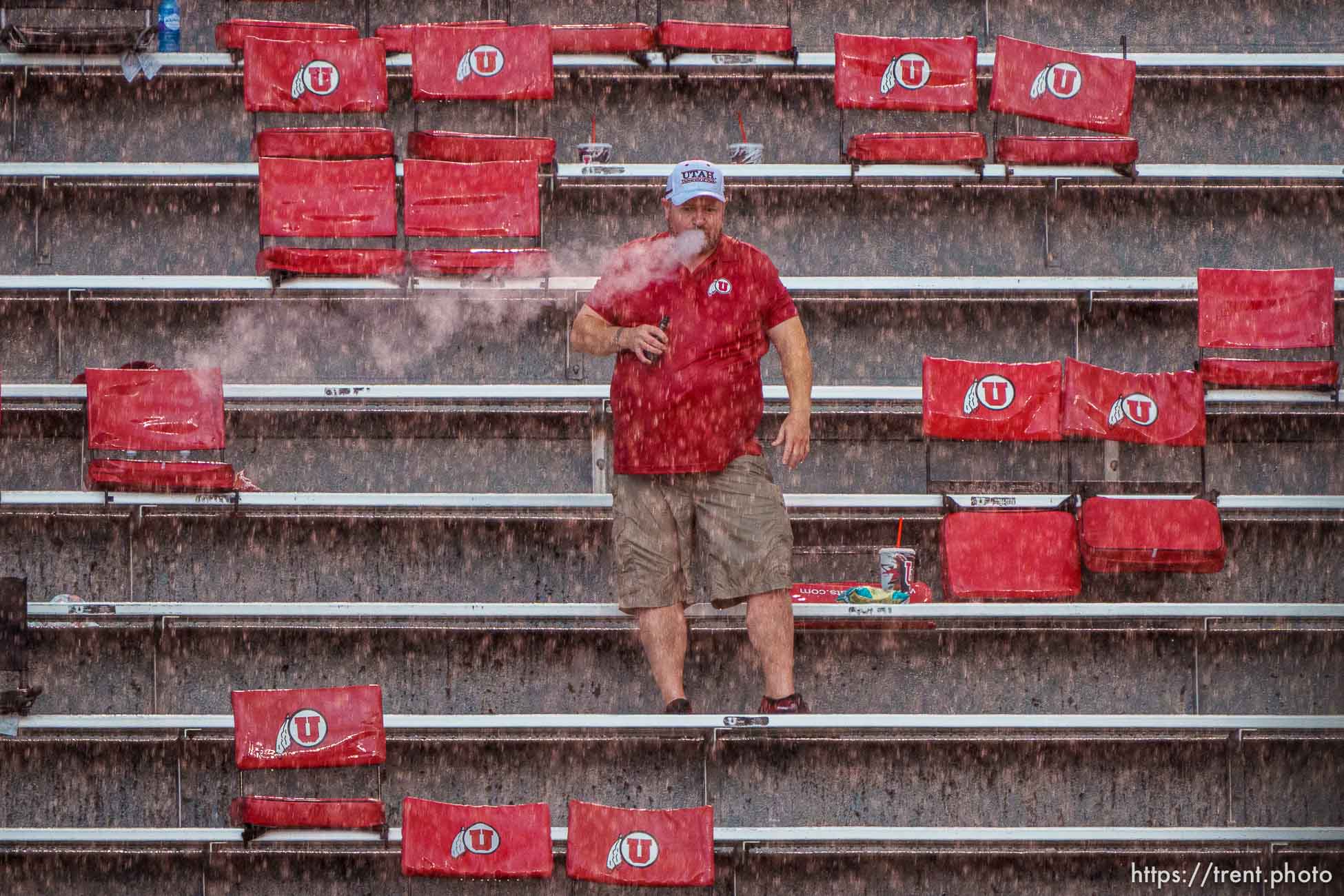 (Trent Nelson  |  The Salt Lake Tribune) Rain pours down on a fan during a lightning delay as the Utah Utes host the Weber State Wildcats in Salt Lake City on Thursday, Sept. 2, 2021.