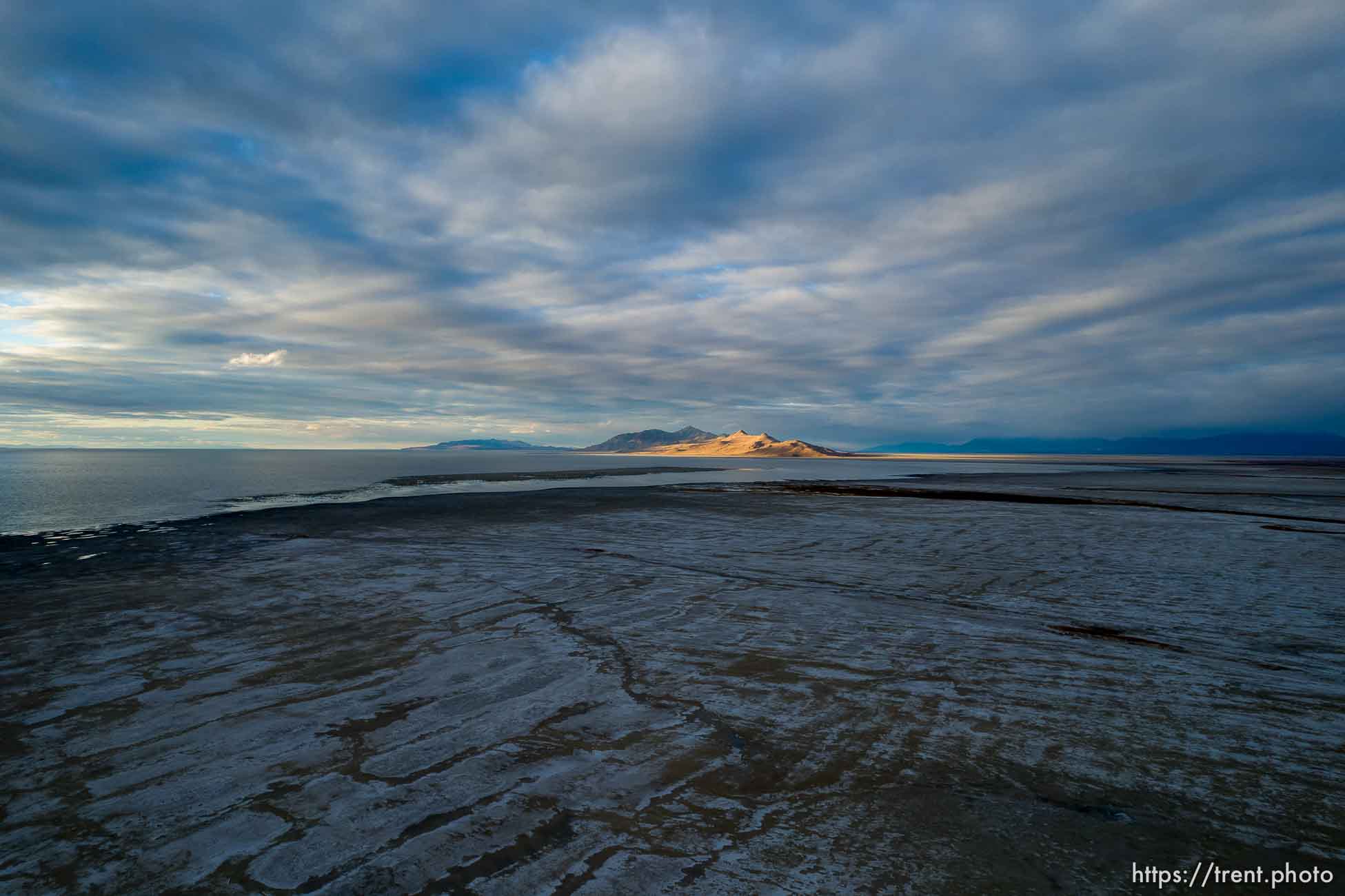 (Trent Nelson  |   The Salt Lake Tribune) The setting sun lights Antelope Island in the distance from the receding shore of the Great Salt Lake on Thursday, Oct. 14, 2021.| The Salt Lake Tribune)