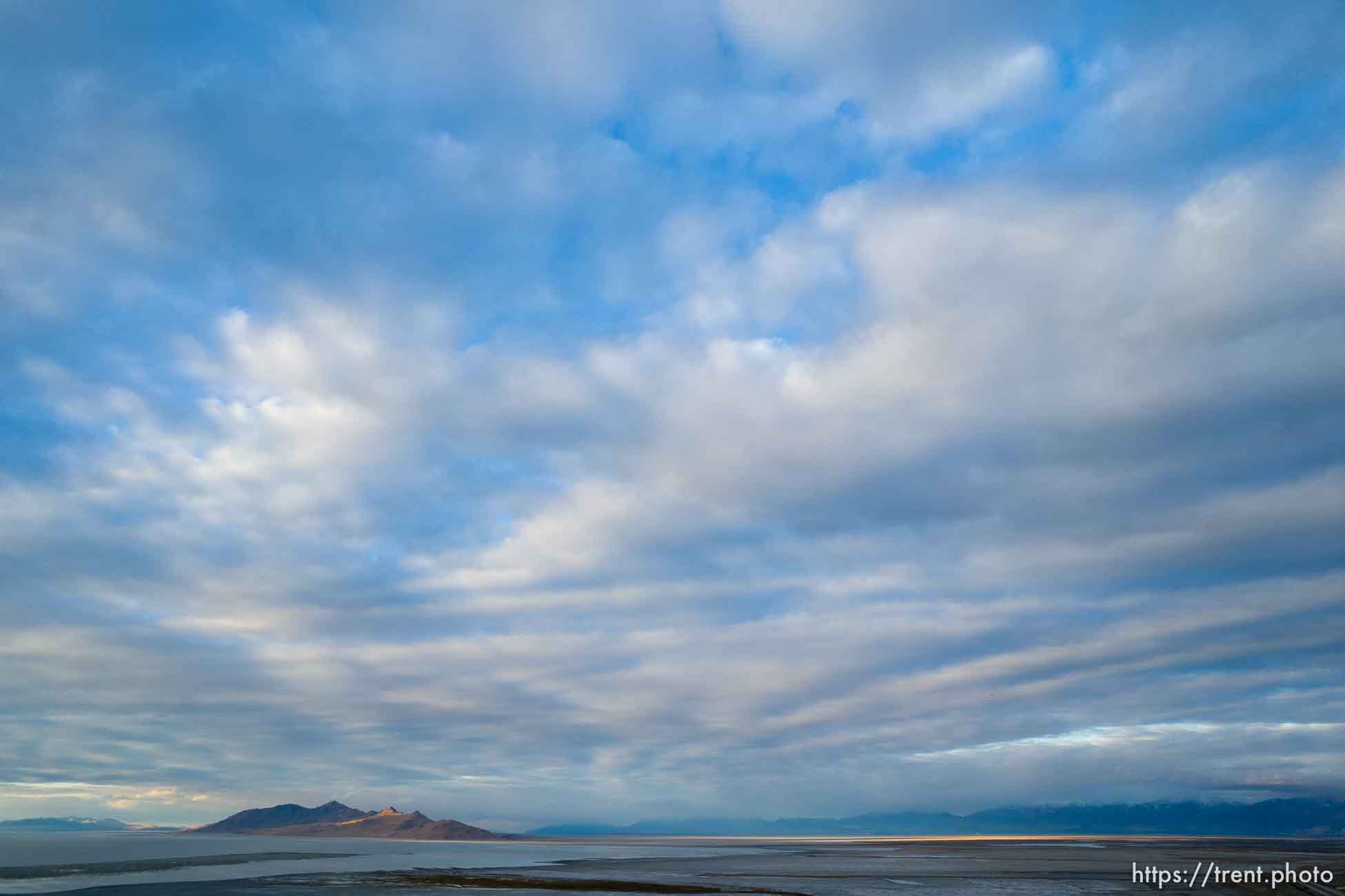 (Trent Nelson  |   The Salt Lake Tribune) The setting sun lights Antelope Island in the distance from the receding shore of the Great Salt Lake on Thursday, Oct. 14, 2021.| The Salt Lake Tribune)