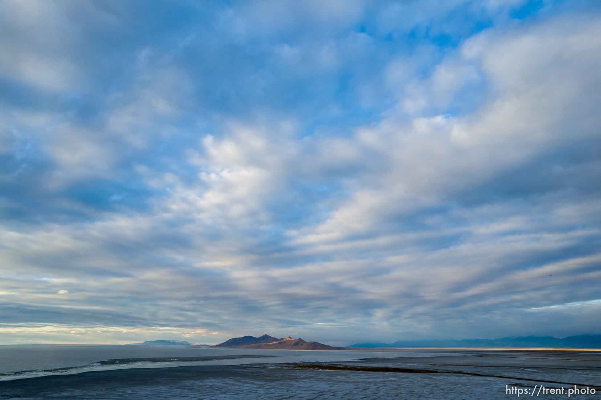 (Trent Nelson  |   The Salt Lake Tribune) The setting sun lights Antelope Island in the distance from the receding shore of the Great Salt Lake on Thursday, Oct. 14, 2021.| The Salt Lake Tribune)