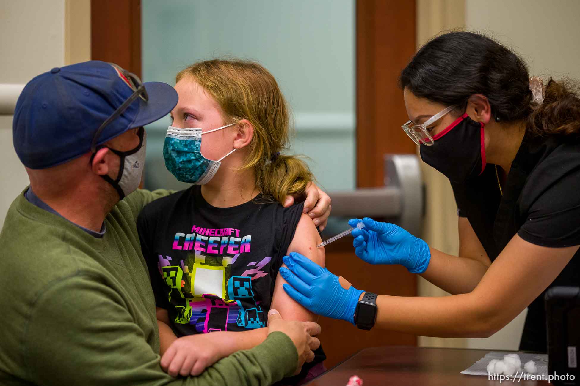 (Trent Nelson  |  The Salt Lake Tribune) Jason Miller holds his daughter, Nina, as she is vaccinated against COVID-19 by Tenzin Drongsar at South Main Public Health Center in South Salt Lake on Wednesday, Nov. 3, 2021.