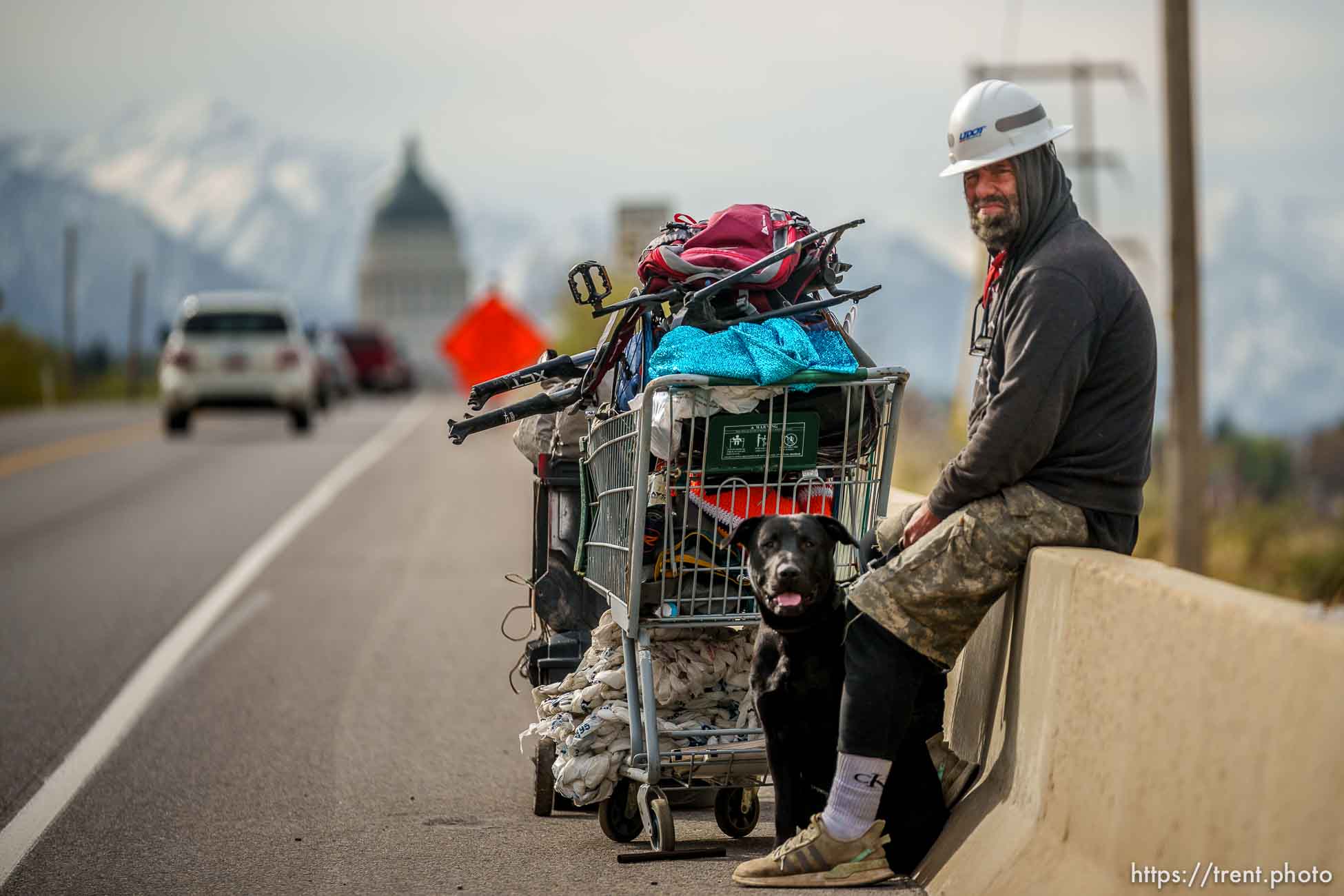 (Trent Nelson  |  The Salt Lake Tribune) A man and his dog sit on the side of Victory Road road as camps are cleared in the foothills north of Salt Lake City on Wednesday, April 27, 2022.