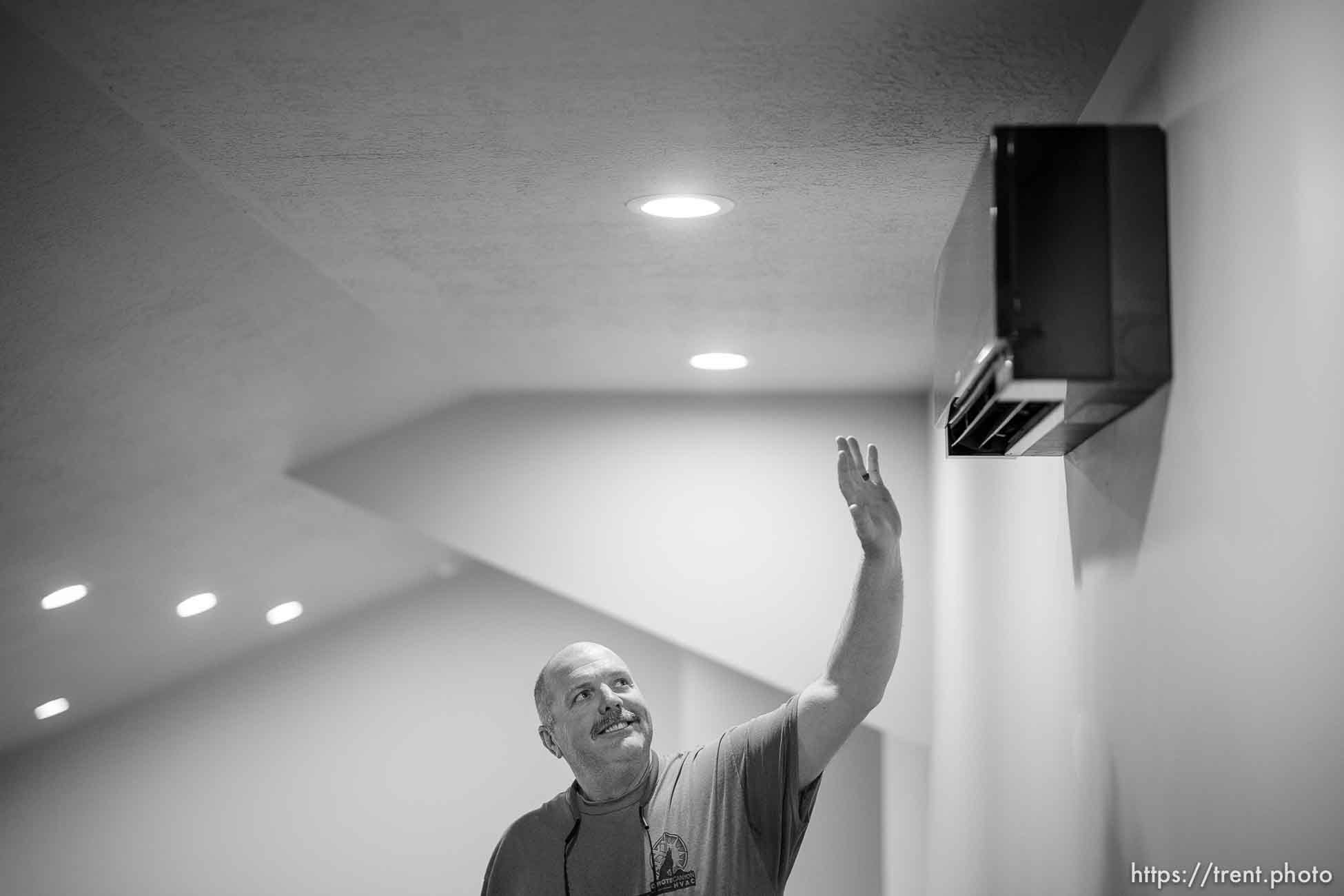 (Trent Nelson  |  The Salt Lake Tribune) Roger Graham reaches up to feel the flow of hot air coming from the electrical heat pump system in his Hooper home on Friday, April 29, 2022.