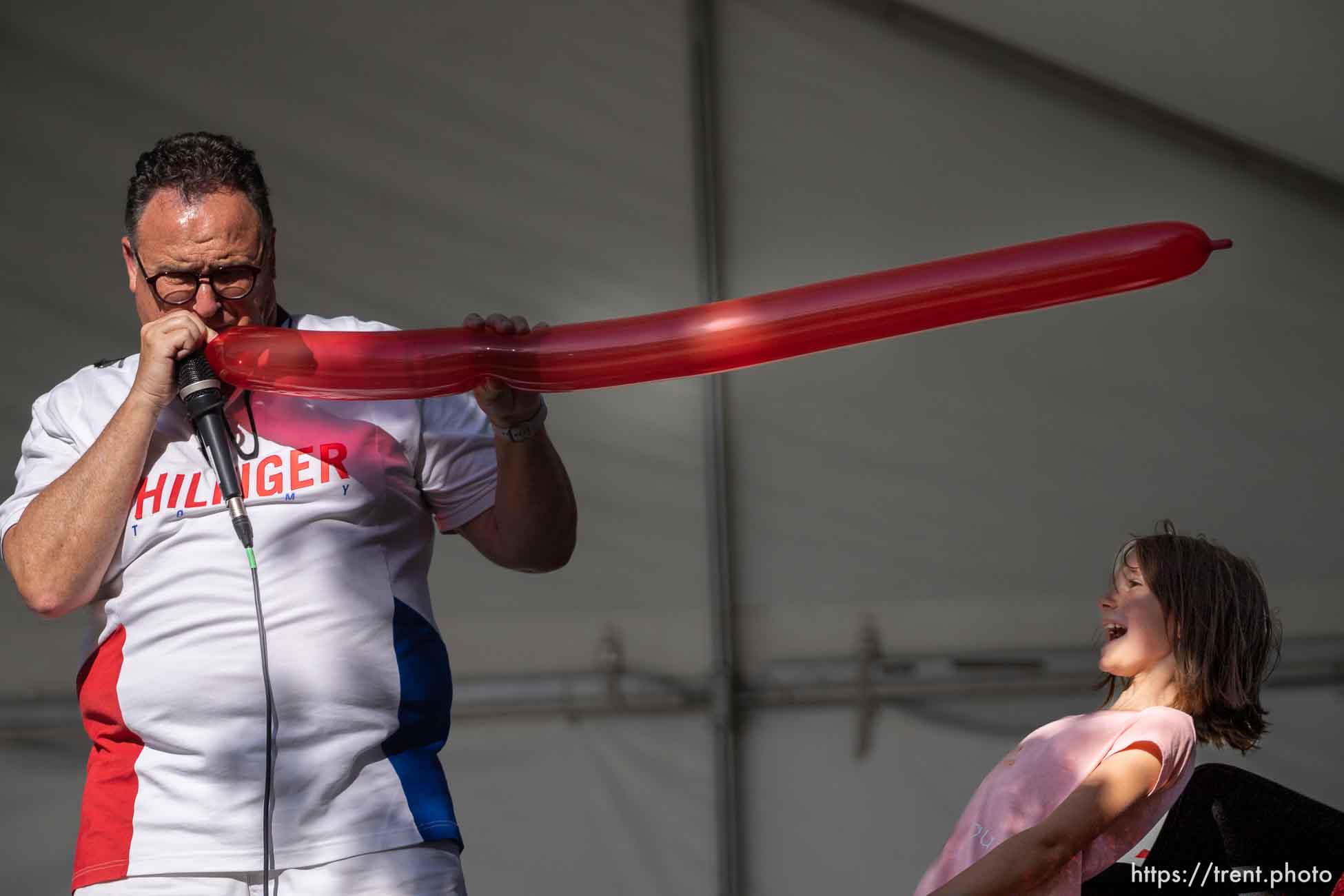 (Trent Nelson  |  The Salt Lake Tribune) Magician Paul Brewer blows up a balloon forcing young volunteer Taylor to lean out of the way at WestFest in West Valley City on Thursday, June 16, 2022.