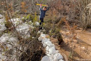 (Trent Nelson  |  The Salt Lake Tribune) Alex Klivecka clears brush to make room for sandbags as water rises sharply in Emigration Canyon on Wednesday, April 12, 2023.