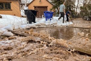 (Trent Nelson  |  The Salt Lake Tribune) People work to save a home as Emigration Creek rises in Emigration Canyon on Wednesday, April 12, 2023.