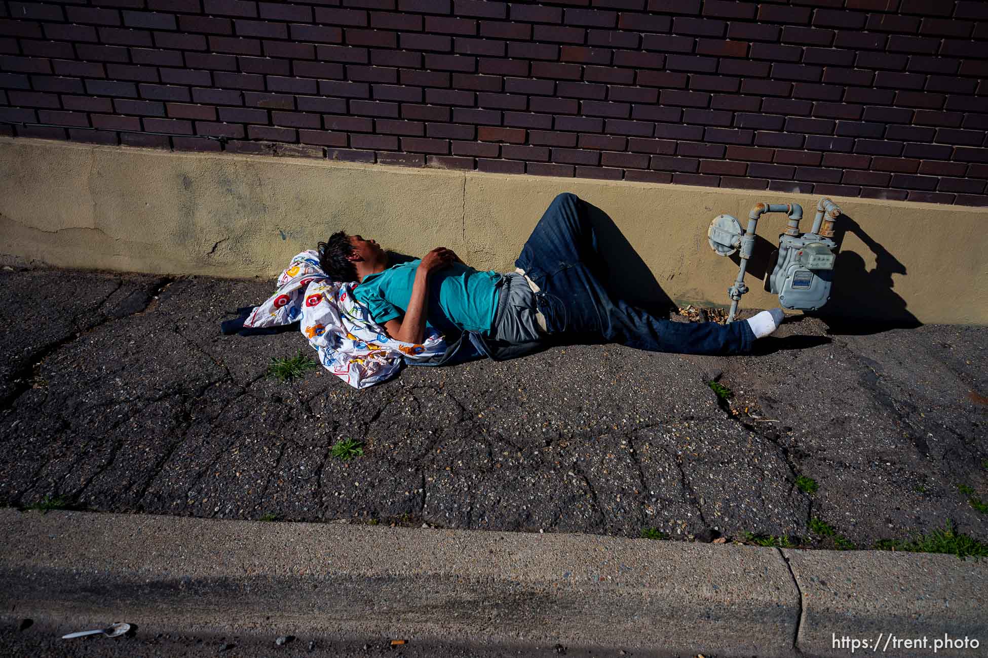 Man sleeping next to building on State Street, Salt Lake City on Wednesday, March 20, 2024.